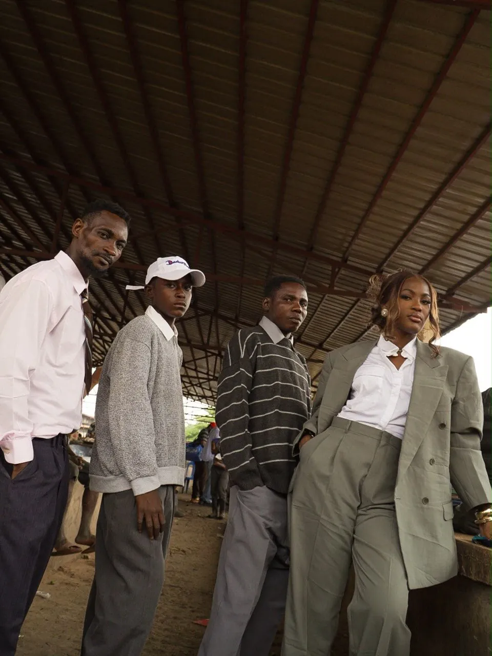 Campagne Mokonzi : quatre silhouettes en tailoring de rue sous le hangar d’un marché de Kinshasa